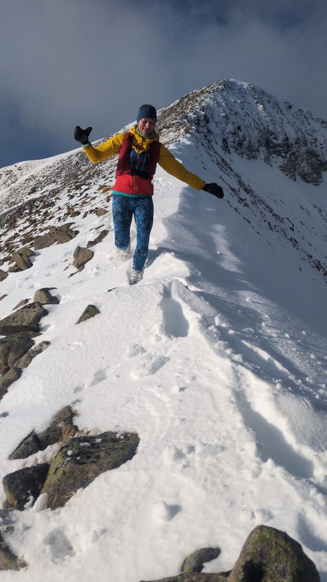 Arms out, running along a snowy winter ridge